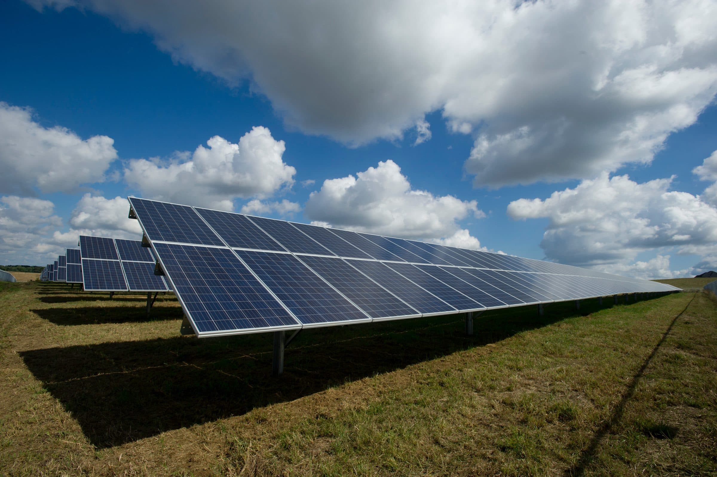 Aerial view of a large ground-mounted solar array beside farmland